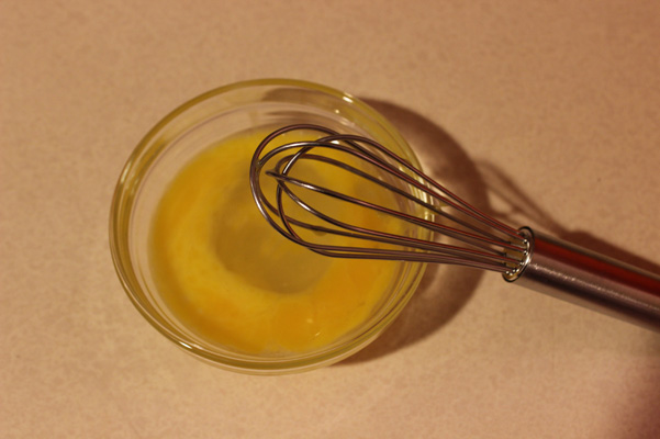 egg in small bowl with tiny whisk